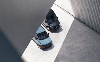 Promotionbild zum bewerben der aktuellen Angebote für Mercedes-Benz Transporter. Der Mercedes-Benz eVito und Mercedes-Benz eSprinter stehen nebeneinander unter einer Brücke aus hellem Stein. 